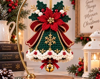May include: A crocheted Christmas bell ornament in dark green with a red poinsettia, white scalloped trim, and gold snowflake accents. The bell features a red ribbon bow, a gold jingle bell clapper, and is suspended from a gold metal display stand.