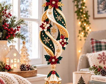 May include: A hanging Christmas ornament featuring a spiraling design in cream, dark green, and gold yarn. It is decorated with crocheted poinsettia flowers, small pearls, and gold snowflake accents. Three small gold bells hang from the bottom.