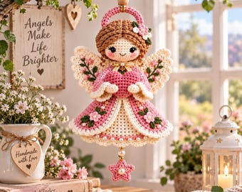 May include: A crocheted angel ornament featuring brown yarn hair, a pink dress with white floral accents, and cream-colored wings. The figure holds a pink heart and is suspended by a string with a small pink star charm at the bottom.