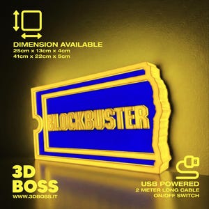 Può includere: Un'insegna rettangolare Blockbuster con centro blu e bordo giallo, illuminata da luce gialla. L'insegna presenta il testo BLOCKBUSTER in lettere gialle. Dimensioni disponibili: 25cm x 13cm x 4cm o 41cm x 22cm x 5cm. Alimentazione USB con cavo da 2 metri e interruttore.