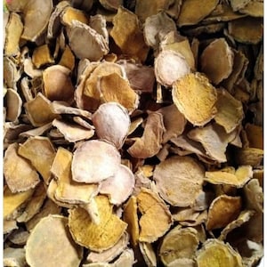 May include: A collection of dried, thinly sliced turmeric root pieces. The slices are irregular in shape and size, displaying a range of earthy tones from pale beige and light tan to deep golden yellow, with a dry, fibrous, and textured surface.