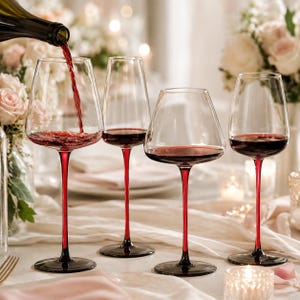 May include: Four clear glass wine glasses with slender red stems and bases. Red wine is being poured from a bottle into the leftmost glass. The glasses feature varying bowl shapes, including tall tapered and wide rounded designs, filled with red wine.