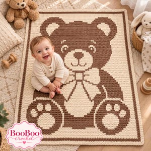 Puede incluir: Una manta de ganchillo rectangular con un gráfico de un oso grande de color marrón sobre un fondo crema. El diseño del oso incluye una pajarita y huellas de patas. La manta tiene un borde marrón oscuro y se muestra con un niño sentado.