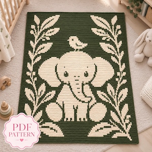 May include: A rectangular crochet blanket featuring a dark green background with a cream-coloured central design of a seated elephant with a small bird perched on its head, framed by two vertical leafy branches. A pink label reads PDF PATTERN.