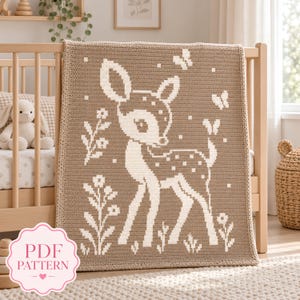 May include: A rectangular crochet blanket featuring a light brown background with a white pixelated design of a young deer standing among flowers and butterflies. A pink circular badge in the corner displays the text PDF PATTERN.