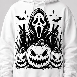 May include: A white hooded sweatshirt featuring a black graphic print of a hooded figure with a mask making a peace sign with both hands, surrounded by three jack-o'-lantern pumpkins, flying bats, and star accents on the front chest area.