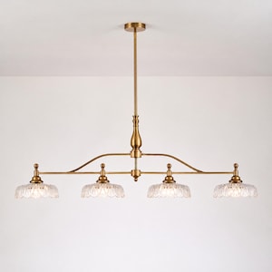 May include: A linear chandelier featuring a central brass rod and a horizontal arm supporting four downward-facing lights. Each light is capped with a clear, scalloped glass shade that has a textured, petal-like pattern on the surface.