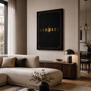 Könnte beinhalten: Ein rechteckiges Wandbild mit einer horizontalen Abfolge goldener Mondphasen, zentriert auf einem einfarbigen schwarzen Hintergrund, eingefasst in einen dünnen schwarzen Rahmen mit goldenen Eckverzierungen, präsentiert an einer neutralen Wand.
