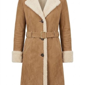 May include: A tan coat with a cream-colored faux shearling lining, wide lapels, and cuffs. The coat features a front button closure, a matching tan belt with a rectangular buckle at the waist, and a hemline trimmed with the same cream-colored material.