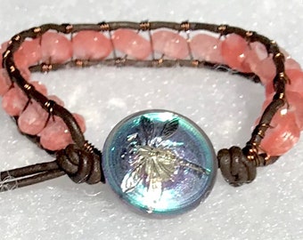 May include: A brown leather bracelet with pink gemstone beads and a dragonfly button.