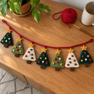 May include: A crocheted garland featuring seven alternating dark green, light green, and white Christmas tree ornaments. Each tree is topped with a yellow star and decorated with small red, white, and yellow yarn bobbles on a red cord.