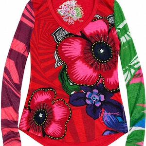 Può includere: Una maglia a maniche lunghe con scollo a V, caratterizzata da una base rossa vivace con grandi motivi floreali rosa e viola. La manica sinistra presenta strisce rosso scuro e rosa, mentre la manica destra è verde con stampe bianche a foglia.