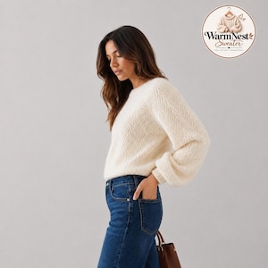Peut inclure: Un pull à manches longues couleur crème avec un motif à chevrons texturé, doté d'une encolure ronde et de poignets côtelés. Le pull est associé à un jean bleu foncé. Un logo circulaire dans le coin affiche le texte WarmNest Sweater.