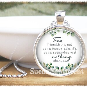 May include: Silver necklace with a round glass pendant featuring a green leafy design and the quote "True friendship is not being inseparable, it's being separated and nothing changes".