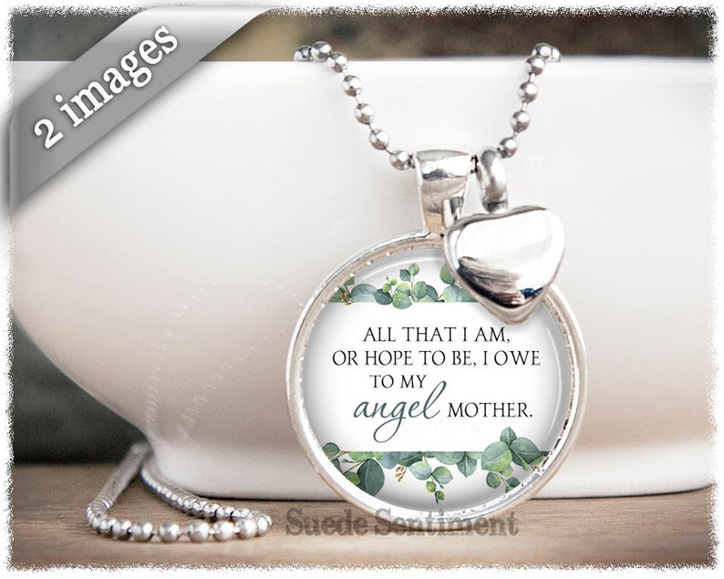 May include: Silver necklace with a round pendant featuring a green floral design and the text "ALL THAT I AM, OR HOPE TO BE, I OWE TO MY angel MOTHER." The pendant is attached to a silver chain with a small silver heart charm.
