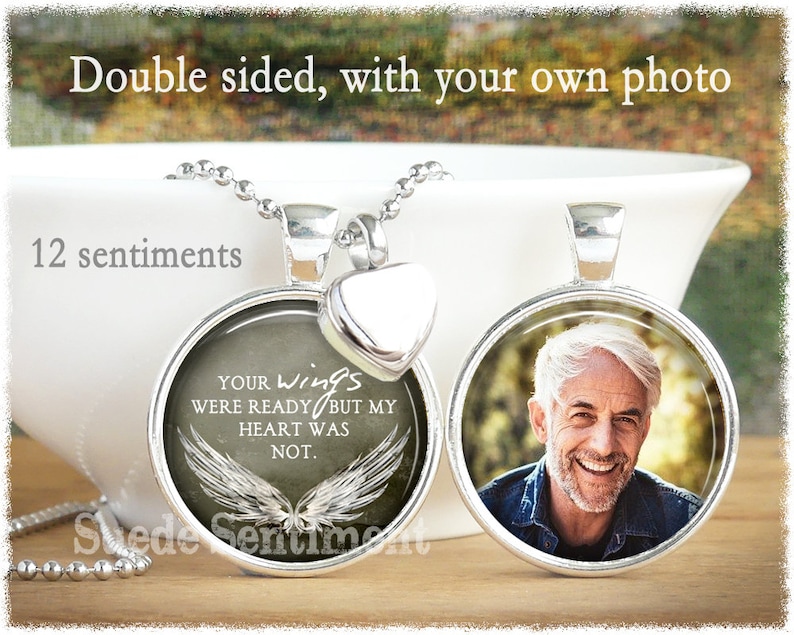 May include: A silver necklace with a round pendant featuring a photo on one side and a sentiment on the other. The sentiment reads "Your wings were ready but my heart was not." The pendant is attached to a silver chain with a heart-shaped charm.