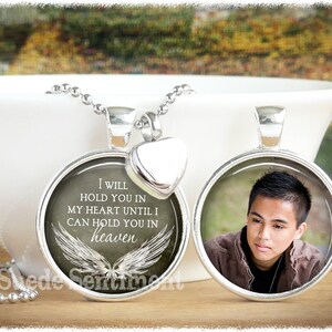 May include: A silver necklace with two pendants. One pendant features a photo of a young man, and the other pendant has a white background with the text "I WILL HOLD YOU IN MY HEART UNTIL I CAN HOLD YOU IN heaven" and a pair of white angel wings.