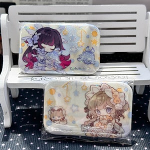 May include: Two rectangular pins featuring anime-style illustrations. The top pin shows a character with dark hair and purple accents labeled Columbina. The bottom pin shows a character with light brown hair labeled Sandrone, both with stars.