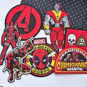 May include: A collection of embroidered fabric patches featuring Marvel characters and symbols. Included are a red Avengers logo, a standing Colossus figure, a Deadpool character, a Marvel Collector Corps emblem, a skull and poop emoji, and a Deadpool Chimichanga Shack patch.