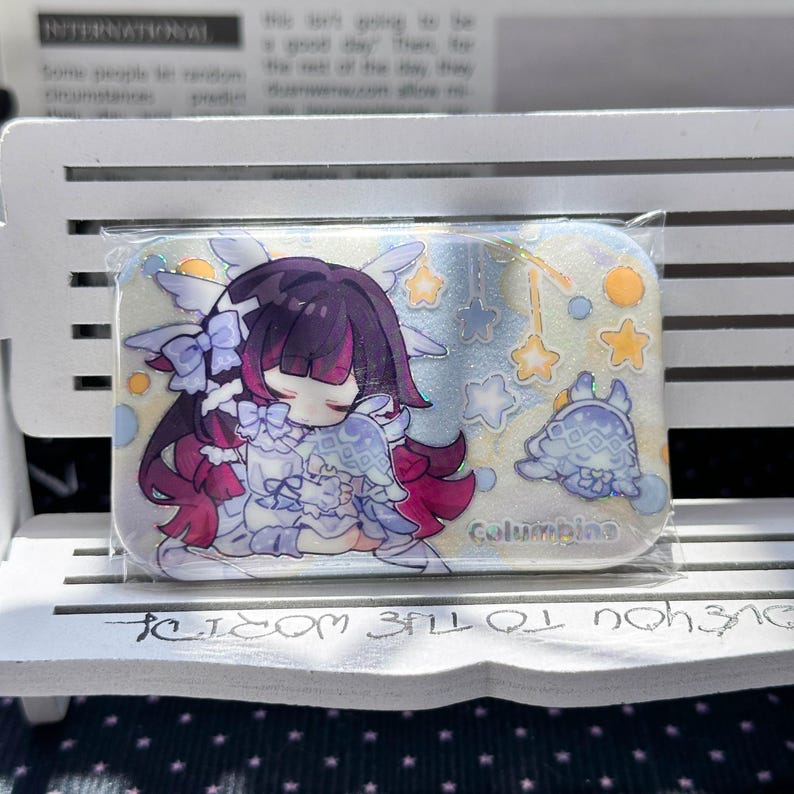 May include: A rectangular pin featuring a glittery finish and an anime-style illustration of a character with dark purple hair and pink highlights, wearing a white outfit with bows. The text Columbina is printed in blue near a small creature.