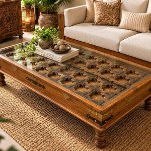 May include: A rectangular wooden coffee table featuring a glass top over a carved, grid-patterned wooden base. The table has four turned legs, brass corner accents, and dark metal hardware along the sides, showcasing a natural wood finish.