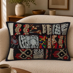 May include: A rectangular throw pillow featuring a patchwork design of various embroidered fabric panels in black, red, white, blue, and gold. The pillow has a dark border and displays intricate floral, paisley, and geometric patterns.