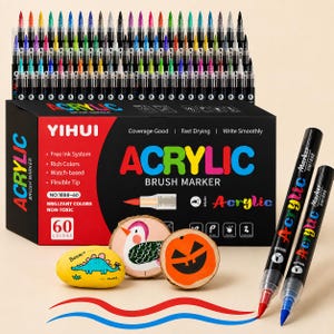 Puede incluir: Un juego de 60 rotuladores de pincel acrílico YIHUI en una caja negra con detalles rojos. La caja muestra texto que incluye "ACRYLIC BRUSH MARKER", "60 COLORS" y "NON-TOXIC". Se muestran tres piedras pintadas y dos rotuladores.