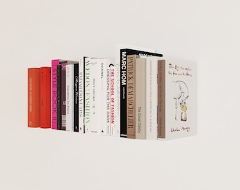 May include: A bookshelf with a variety of books, including "The School of Fashion", "Dressing for the Dark", "Marc Hom Portraits", "The Great Gatsby", "The Boy, The Mole, The Fox and The Horse", and "Style Book II".