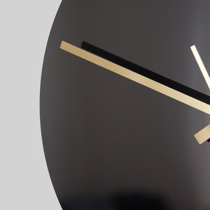 May include: A black clock face with gold hour, minute, and second hands.