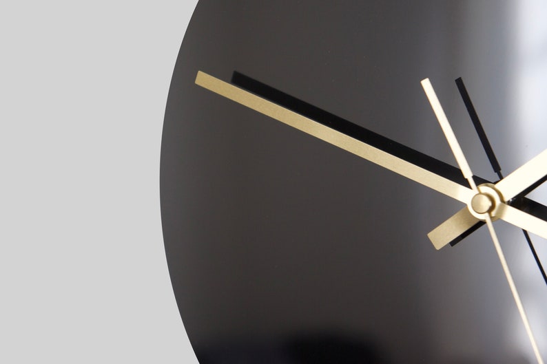 May include: A black clock face with gold hour, minute, and second hands.