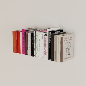 May include: A selection of hardback books with visible spines, displaying titles such as "STYLE BOOK II" and "CHANEL." The books are in various colours and are arranged on a white surface.