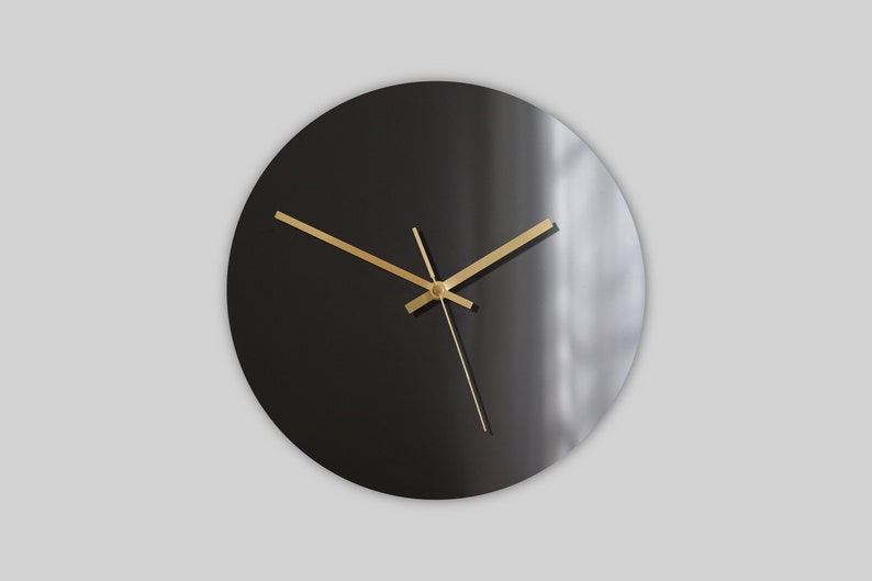 May include: A black round clock with gold hands. The clock face is plain and has no numbers.
