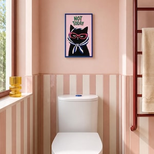 Peut inclure: Une impression murale rectangulaire dans un cadre bleu représentant un chat noir portant des lunettes œil-de-chat roses et un foulard rayé bleu et blanc. Le texte NOT TODAY est imprimé en vert au-dessus du chat sur un fond rose clair.