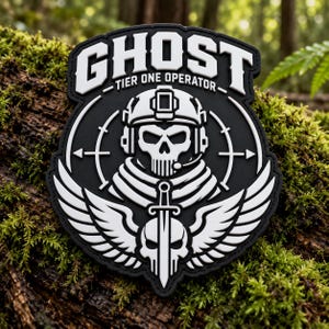 Könnte beinhalten: Ein schwarz-weißes taktisches Aufnäher-Abzeichen mit einem Totenkopf, der einen taktischen Helm und ein Headset trägt, unter dem Text GHOST TIER ONE OPERATOR. Ein Schwert ist vertikal vor einem zweiten Totenkopf mit Flügeln an beiden Seiten platziert.