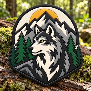 Puede incluir: Un parche en forma de escudo con una cabeza de lobo estilizada en negro, gris y blanco. El fondo muestra pinos verdes, picos de montañas grises y un sol amarillo sobre un cielo crema, todo encerrado en un borde negro grueso.