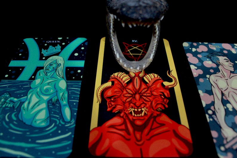 May include: Three tarot cards with colorful illustrations. The card on the left shows a woman with a crown, the middle card shows a red demon with multiple eyes and horns, and the card on the right shows a man with a blue background.