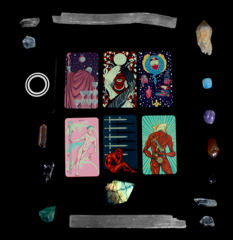 May include: A tarot card spread with nine cards laid out in a grid pattern. The cards are illustrated with colorful, fantastical imagery. The cards are surrounded by various crystals and stones.