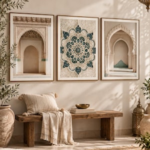 May include: A triptych of framed wall art featuring two prints of architectural archways and one central print of a detailed teal and beige mandala pattern. The artwork is displayed in thin brown frames above a wooden bench with a textured throw blanket.
