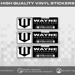 Puede incluir: Tres pegatinas de vinilo rectangulares con un diseño en blanco y negro, que presentan un logotipo W estilizado a la izquierda y el texto Property of Wayne Enterprises Official Asset Tracking Label con un código de barras a la derecha.