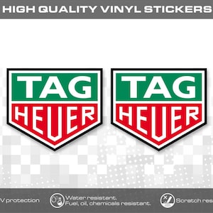 Könnte beinhalten: Zwei schildförmige Vinylaufkleber mit dem TAG HEUER-Logo, bestehend aus einem grünen oberen und einem roten unteren Bereich, getrennt durch eine weiße Linie. Oben steht der Text HIGH QUALITY VINYL STICKERS, ergänzt durch Symbole für Beständigkeit.