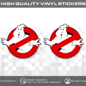 Peut inclure: Deux autocollants en vinyle circulaires représentant un personnage fantôme blanc centré dans un cercle rouge barré d'une ligne diagonale rouge. Le texte HIGH QUALITY VINYL STICKERS figure en haut, avec des icônes pour la protection UV, la résistance à l'eau et aux rayures.