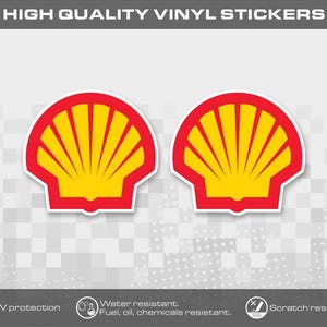 Könnte beinhalten: Zwei Vinyl-Aufkleber mit dem ikonischen Shell-Logo in leuchtendem Gelb und Rot. Der Text HIGH QUALITY VINYL STICKERS steht oben, während Symbole unten auf UV-Schutz sowie Beständigkeit gegen Wasser, Kraftstoff, Öl und Chemikalien hinweisen.