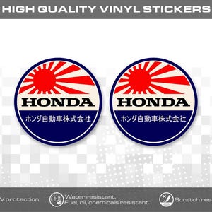 Könnte beinhalten: Zwei kreisförmige Vinylaufkleber mit einem roten Sonnenstrahlen-Design über dem Text HONDA und japanischen Schriftzeichen. Die Aufkleber haben einen dunkelblauen Rand und einen weißen Hintergrund. Oben steht der Text HIGH QUALITY VINYL STICKERS.