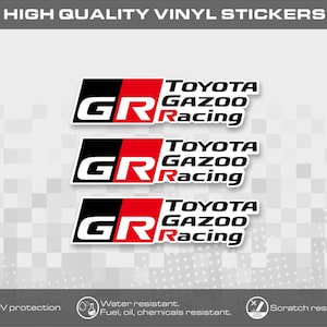 Może przedstawiać: Trzy prostokątne naklejki winylowe z logo Toyota Gazoo Racing w kolorze czarnym, czerwonym i białym. Projekt zawiera litery GR pogrubioną czcionką obok tekstu Toyota Gazoo Racing. Górny tekst brzmi HIGH QUALITY VINYL STICKERS.
