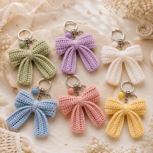 Peut inclure: Six porte-clés nœuds en crochet de couleur vert sauge, lavande, blanc, bleu clair, rose poudré et jaune pâle. Chaque nœud est doté d'un anneau en métal argenté, d'un petit fermoir mousqueton et d'une perle ronde de couleur pastel assortie.