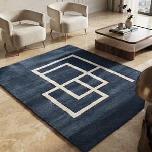 May include: A rectangular area rug featuring a deep navy blue background with a contrasting white geometric pattern consisting of interconnected square and rectangular outlines centred on the surface of the soft, textured floor covering.