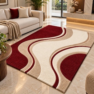 Puede incluir: Una alfombra rectangular con un diseño abstracto audaz de líneas curvas y fluidas. La alfombra presenta una paleta de colores rojo intenso, beige suave y crema, con secciones texturizadas que crean un efecto visual ondulado.