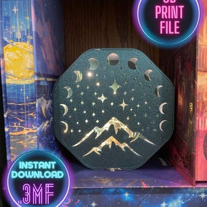 Puede incluir: Lámpara octogonal de color verde azulado oscuro, impresa en 3D, con un diseño celestial. La lámpara presenta estrellas recortadas, medias lunas y siluetas de montañas. El texto "3D PRINT FILE" y "INSTANT DOWNLOAD .3MF" son visibles.