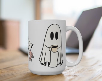 May include: A white ceramic mug featuring a black-outlined illustration of a ghost holding a small beige coffee cup. To the left of the ghost, a partial view of a second ghost wearing pink roller skates is visible on the smooth white surface.