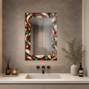 May include: A rectangular wall mirror featuring a decorative border with a swirling, multi-colored pattern of deep red, teal, and cream-colored segments. The frame displays a textured, mosaic-like design with intricate, interconnected shapes.